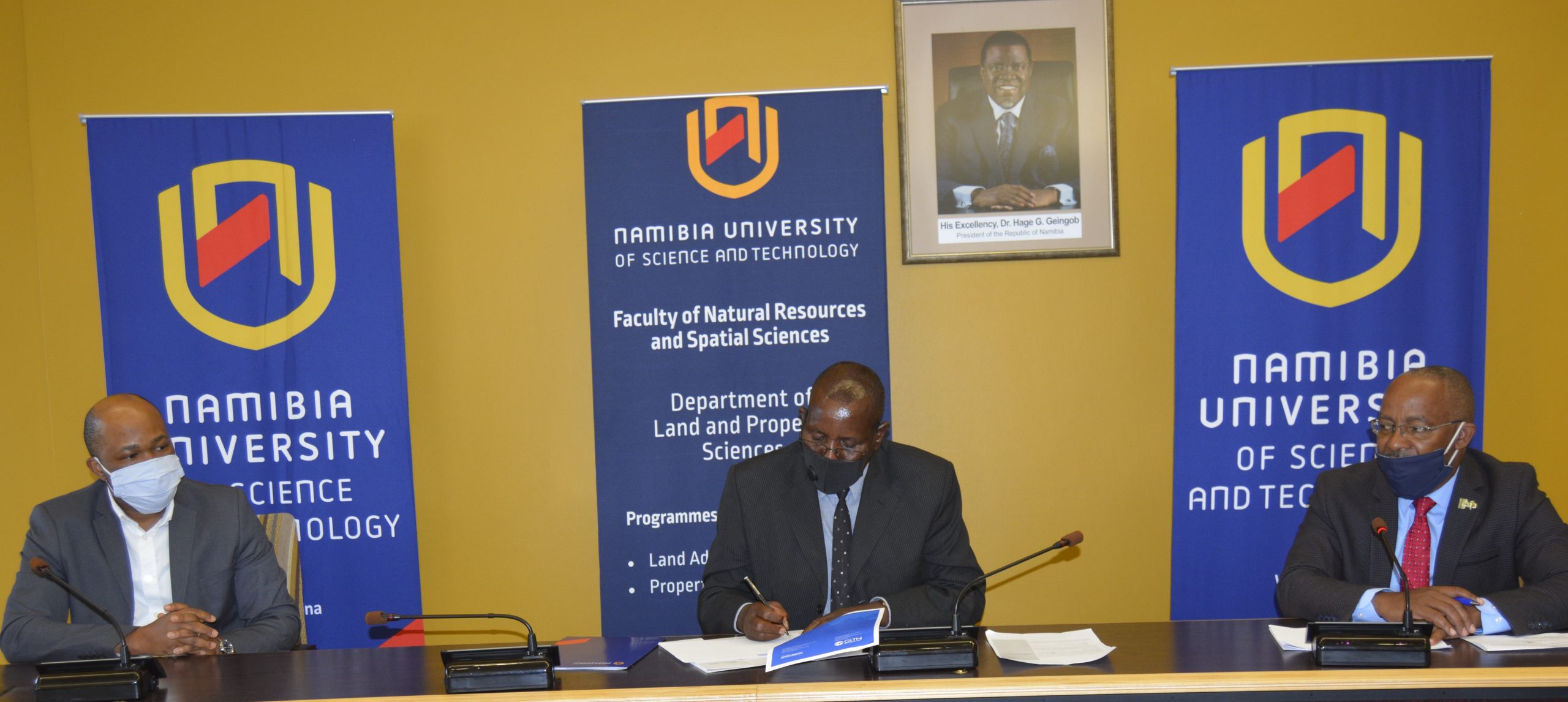 Andrew Niikondo, Acting Vice Chancellor signs the GLTN Partners' Charter witnessed by Prof Mutjinde Katjiua (right) and Prof Uchendu Chigbu (left)